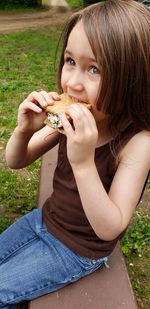 Cute girl eating sweet food while looking away outdoors