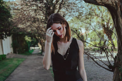 Young woman looking away while standing on tree