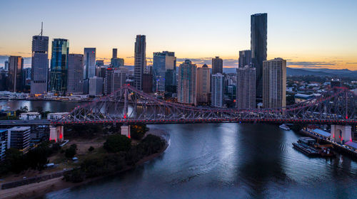 Bridge over river amidst buildings in city against sky