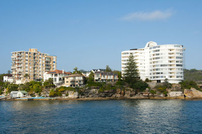 Buildings by sea against clear sky