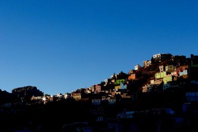 Illuminated cityscape against clear blue sky at night