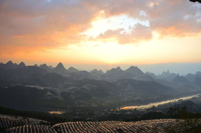 Scenic view of mountains against dramatic sky during sunset