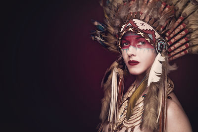 Portrait of young woman wearing headdress against colored background