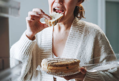 Attractive friendly brunette woman middle age in cozy cardigan eating cake 