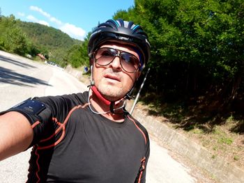 Portrait of man wearing cycling helmet and sunglasses on road during summer