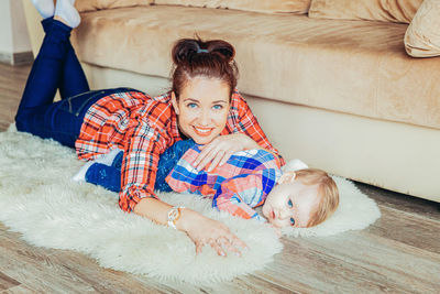 Portrait of mother and daughter lying on floor at home