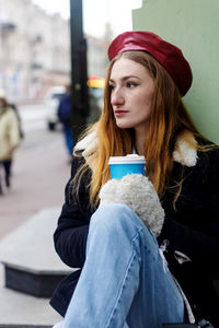 Portrait of smiling young woman sitting on road