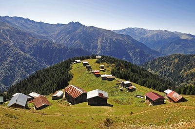 Houses on field by mountains against sky