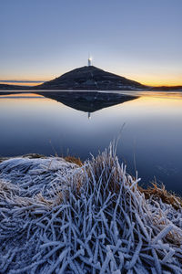 Scenic view of frozen lake against clear sky during sunset