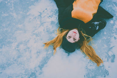 Portrait of young woman lying on snowfield