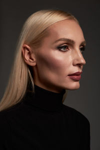 Portrait of beautiful young woman against black background