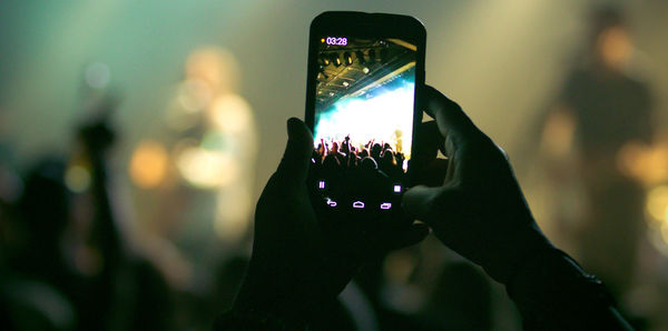 Cropped image of person photographing at music concert