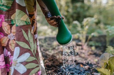 Cropped image of girl watering plants in garden