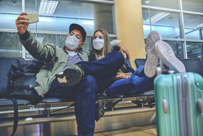 Happy young loving couple waiting for boarding in airport terminal. they are embracing and smiling