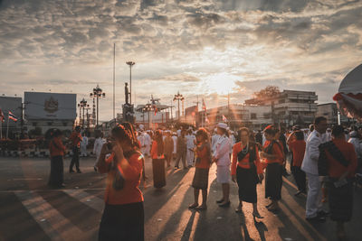People standing on street against sky during sunset