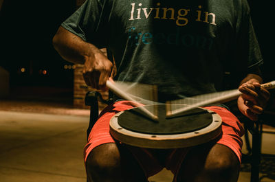 Midsection of man playing drum