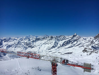 Construction crane on top of klein matterhorn with matterhorn  in the background against blue sky