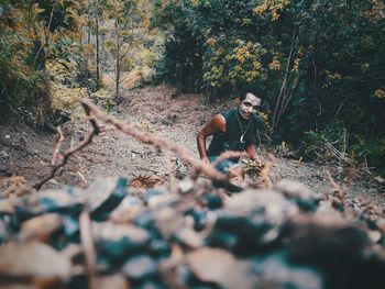 Portrait of man with painted face in forest against trees