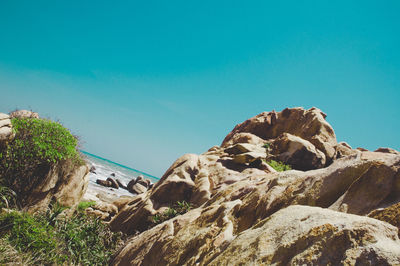 Rocks on shore against clear blue sky