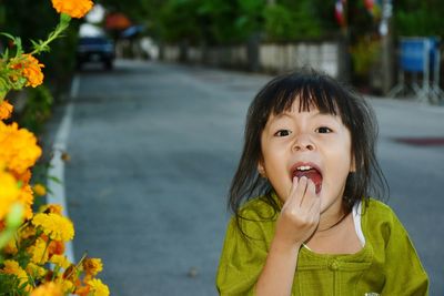 Close-up portrait of girl eating food standing outdoors