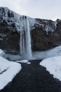 Scenic view of waterfall against sky during winter