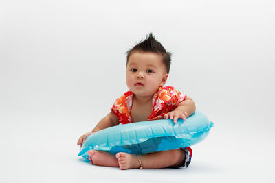 Portrait of cute baby sitting against white background