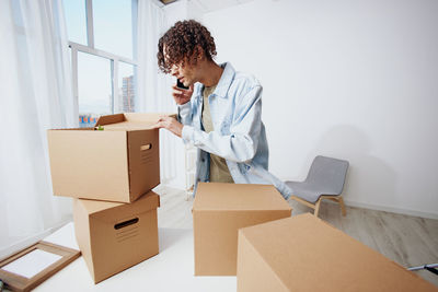 Man talking on phone with cardboard boxes on table