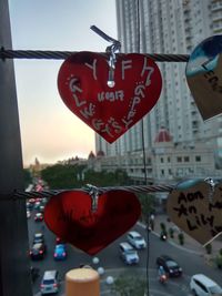 Close-up of red heart shape hanging on window