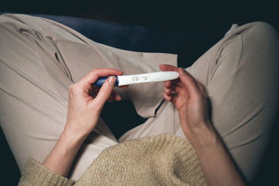 Midsection of woman holding thermometer