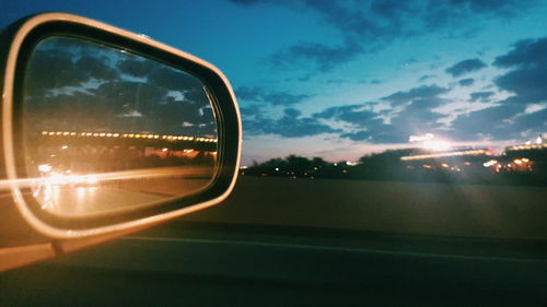 Cars on road against cloudy sky