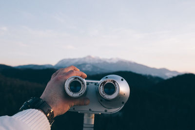 Close-up of hand holding camera against mountain