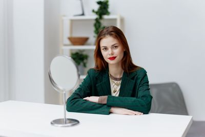 Portrait of young woman using mobile phone while sitting at home