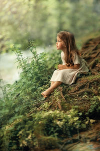 Little girl dreams of becoming a princess sitting in an enchanted forest