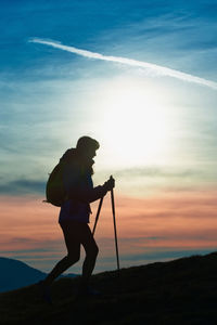 Rear view of man standing by sea against sky during sunset