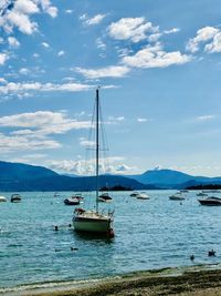 Sailboats moored on sea against sky