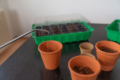 Watering can spout with water dripping into a pot of soil