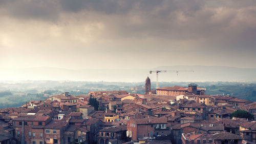 View of cityscape against cloudy sky