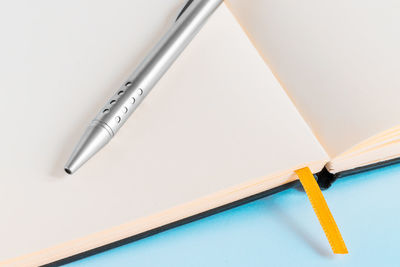 High angle view of pen on blank diary against blue background