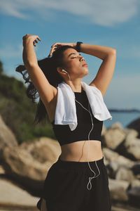 Side view of young woman standing against sky