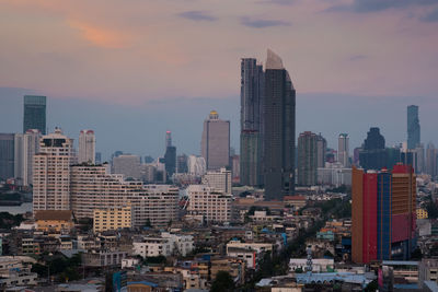 Modern buildings in city against sky during sunset