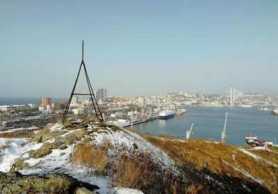 Sailboats in city by sea against clear sky