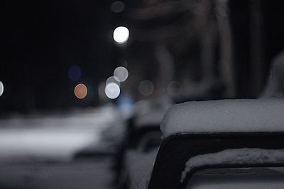 Close-up of snow on illuminated street in city at night