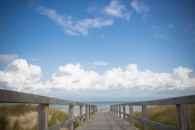 Pier leading towards girl standing at beach