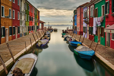 Boats moored in canal against sky