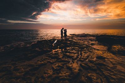 Silhouette man standing on beach against sky during sunset