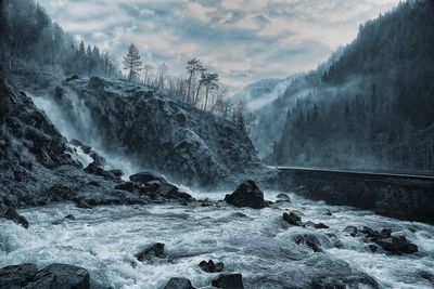 Scenic view of river flowing from mountain against sky