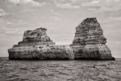 Rock formation by sea against sky
