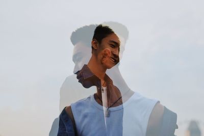 Double exposure image of happy young men standing against sky