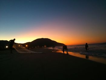 Silhouette of people on beach at sunset