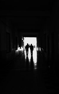 Silhouette men walking in corridor of building
